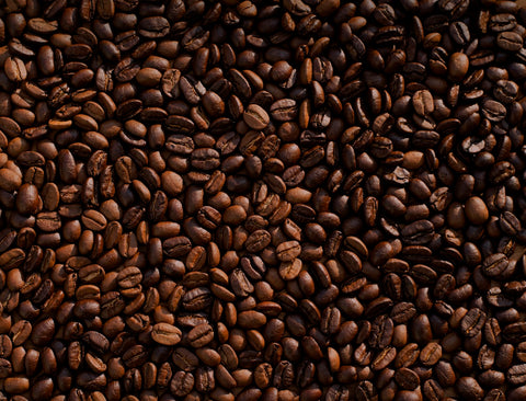 Grains de café arabica sur une surface sombre avec lumière naturelle chaude